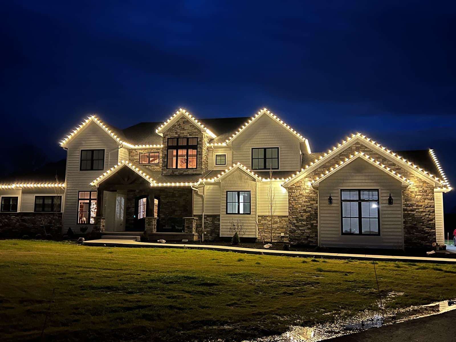 Professional holiday lighting installed along a home's rooflines at dusk